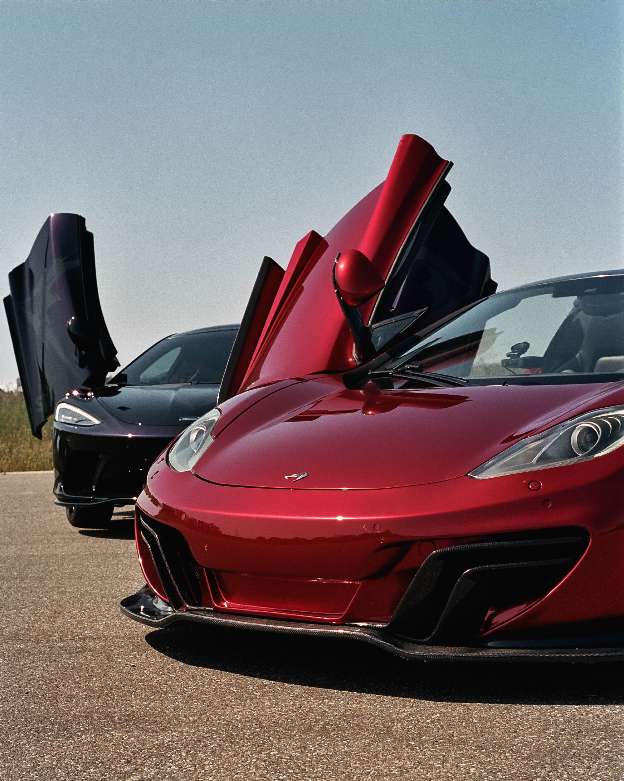 Red and black McLaren supercars with dihedral doors raised