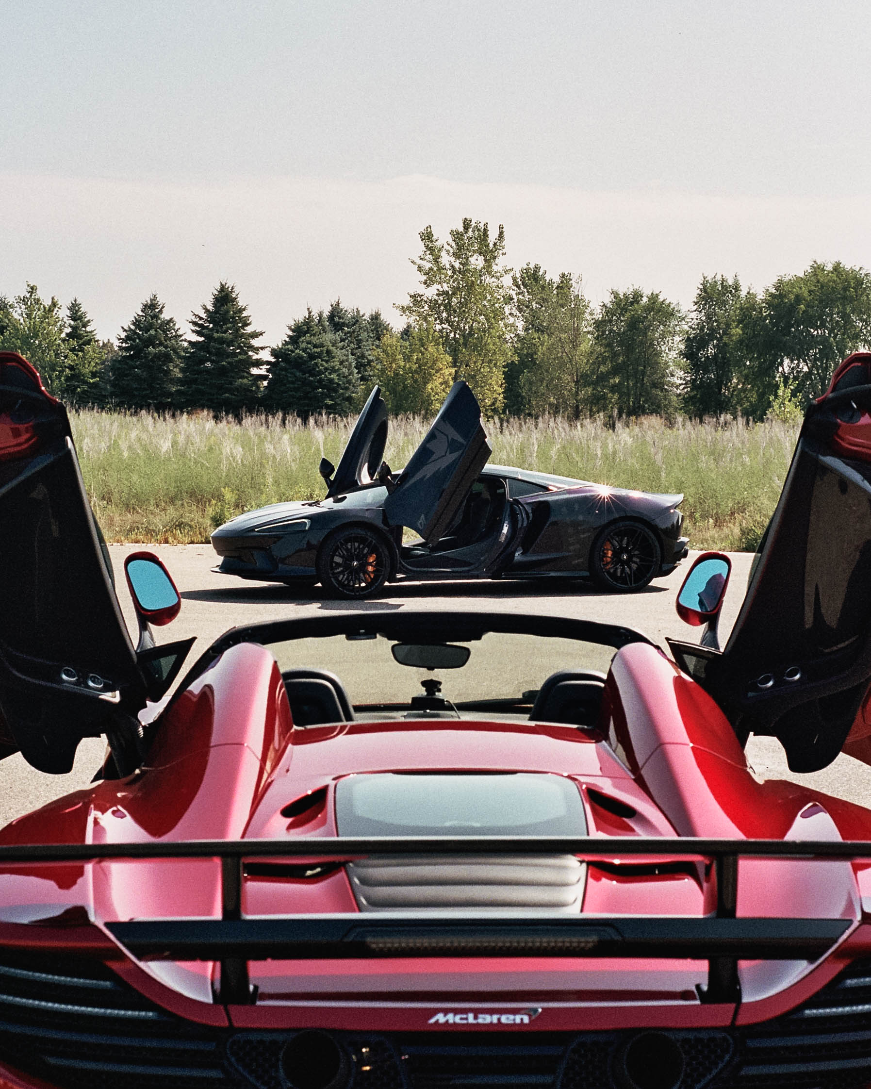 Red McLaren rear framing a second supercar
